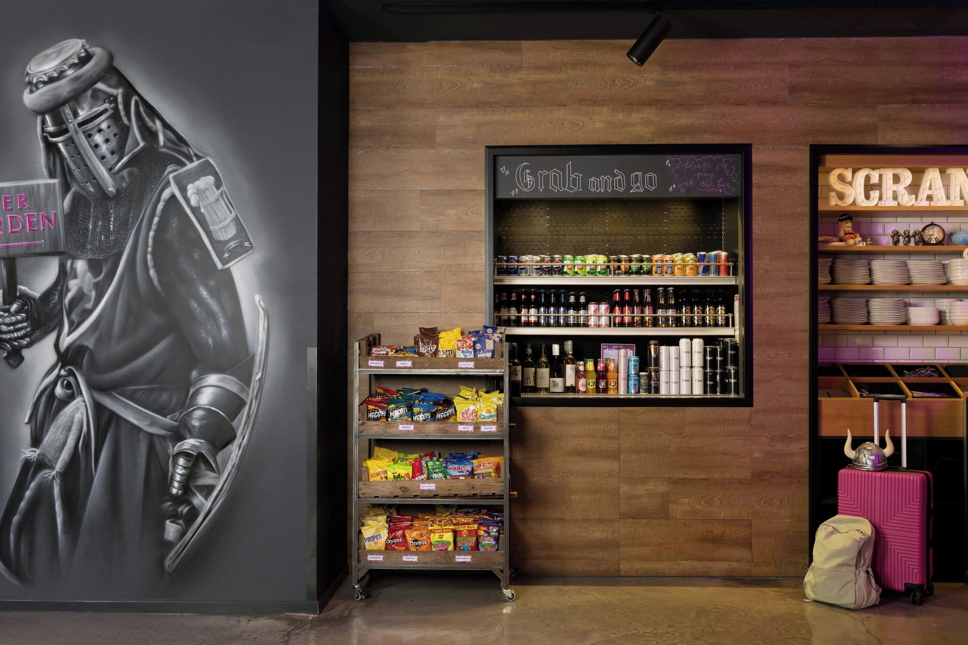 Una pared con un mural de un caballero, repisas con aperitivos y un letrero que dice "The Grab and Go".