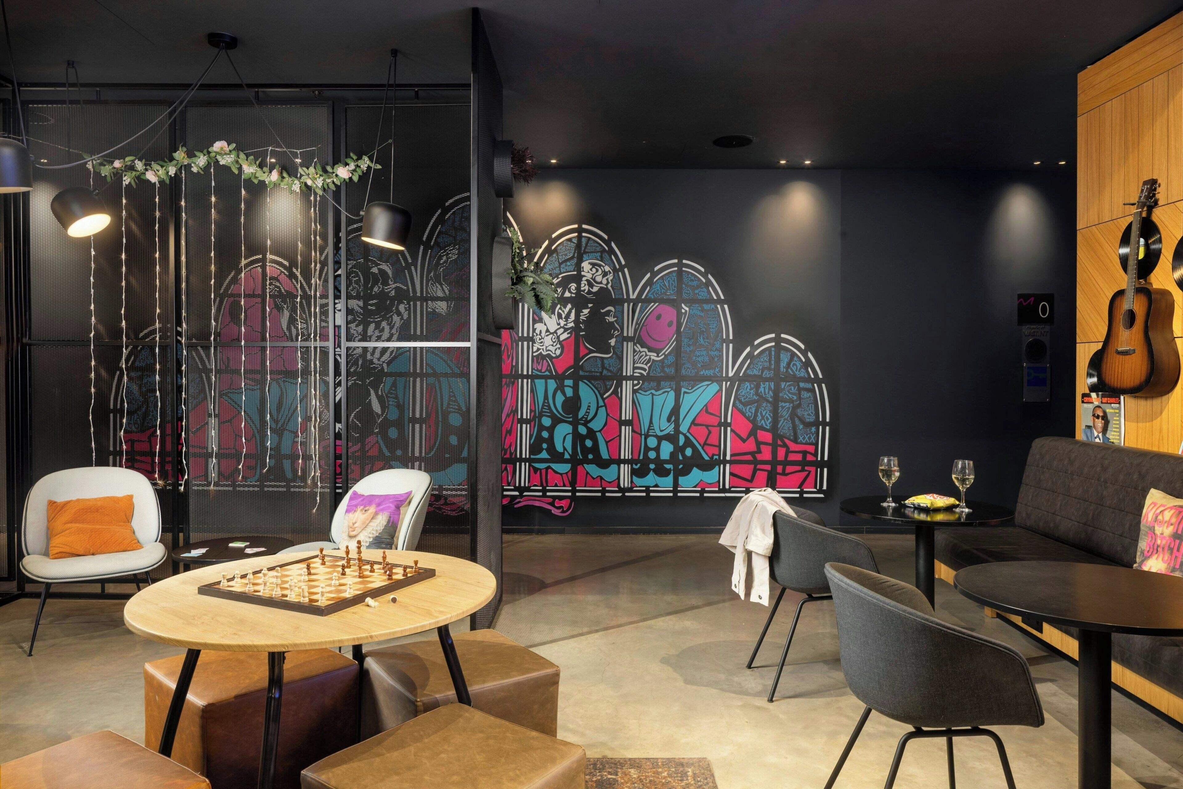 A modern lounge area with a chess table, comfortable seating, and a vibrant graffiti wall.