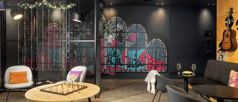 A modern lounge area with a chess table, comfortable seating, and a vibrant graffiti wall.