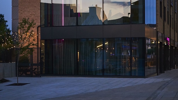 A modern building with large glass windows and a neon sign. - Moxy York (York)