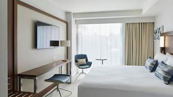 Una habitación de hotel con una cama grande, un escritorio con una silla, un televisor y una mesita.