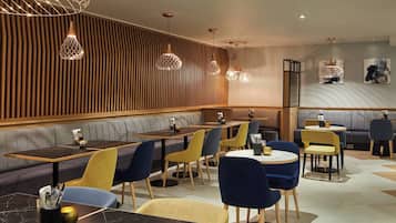 Un interno ristorante moderno con pannelli in legno, sedute imbottite e lampade pendenti di design.
