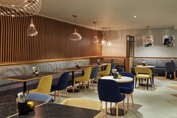 Un intérieur de restaurant moderne avec des lambris en bois, des sièges rembourrés et un éclairage contemporain suspendu.