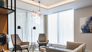 Een moderne hotelkamer met grote ramen, een wereldbol op een bijzettafeltje en een minimalistische inrichting.