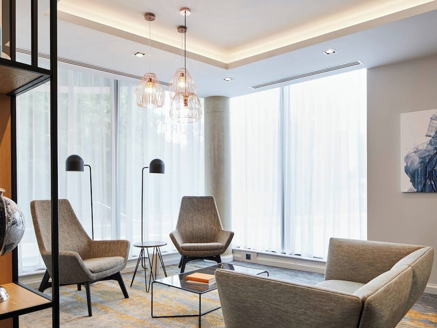 Ein modernes Hotelzimmer mit großen Fenstern, einem Globus auf einem Beistelltisch und einer minimalistischen Einrichtung.