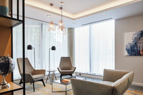 A modern hotel room with large windows, a globe on a side table, and a minimalist decor.