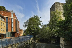 A riverside view with a stone bridge, a modern building labeled "Courtyard," and lush greenery.