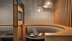 Een moderne, gezellige zithoek met een laptop op een tafel, een kopje en een lijstje aan de muur.