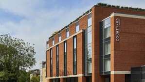 Een modern gebouw van baksteen met grote ramen en een bord waarop 