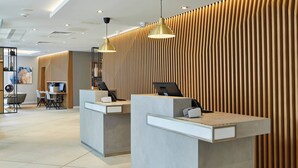 Een receptie met twee balies, moderne verlichting en een wand van houtpanelen.