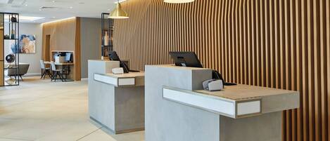 A reception area with two counters, modern lighting, and a wooden panel wall.