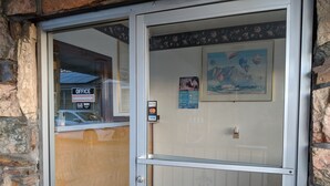 A hotel entrance with a glass door, a reception desk, and a framed picture on the wall.
