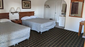 A hotel room with two beds, a bathroom, and a small sitting area.