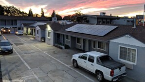 A parking lot with a white pickup truck, a building with a solar panel, and a clear sky with clouds.