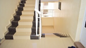 A staircase with alternating black and beige steps, white handrails, and a view of a balcony with railings. - 254 Airport Inn (Syokimau)