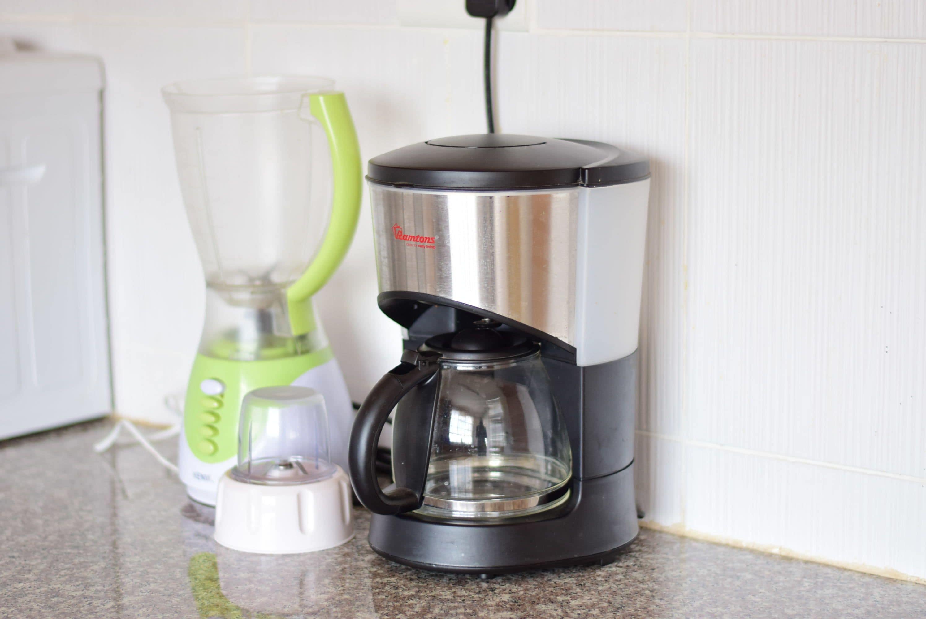 A kitchen with a coffee maker, a blender, and a kettle on the counter.