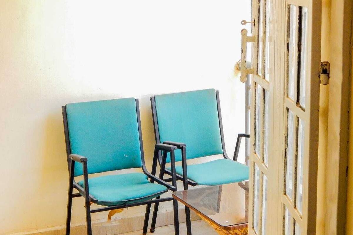 Two teal chairs with black frames and a glass table, positioned near a white door with a metal handle.