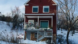 A two-story house with a red exterior, a front porch, and a garage.