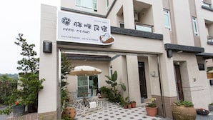 A modern building with a sign for a pet-friendly establishment, outdoor seating, and potted plants. - Pang Mi B&B (Taitung)