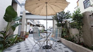 An outdoor patio with a table and chairs, a large umbrella, and potted plants. - Pang Mi B&B (Taitung)