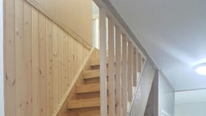 Eine Holztreppe mit Handlauf, die zu einer oberen Etage führt.