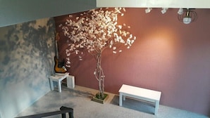 Ein Zimmer mit einem kleinen Kunstbaum, einer Gitarre und einer Sitzbank.