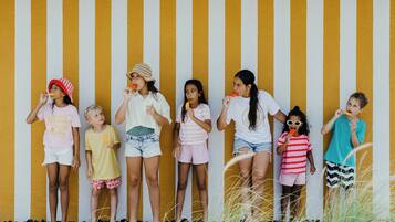 A group of children standing against a striped wall.