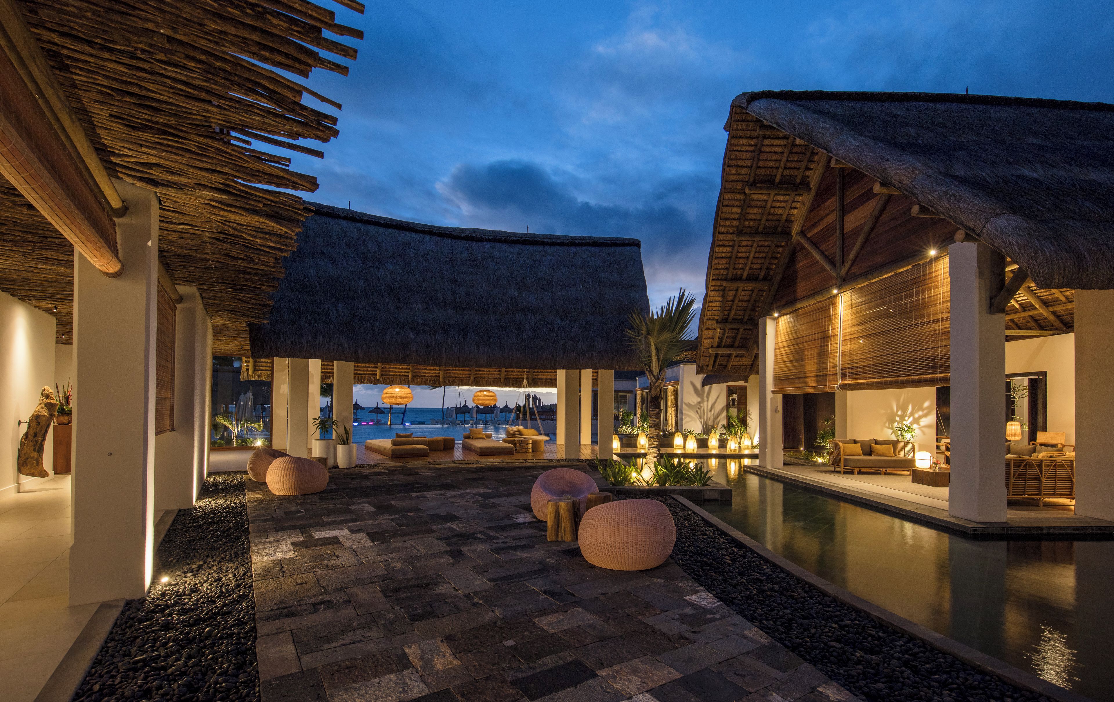 A resort with thatched-roof structures, a pool, and outdoor seating areas.