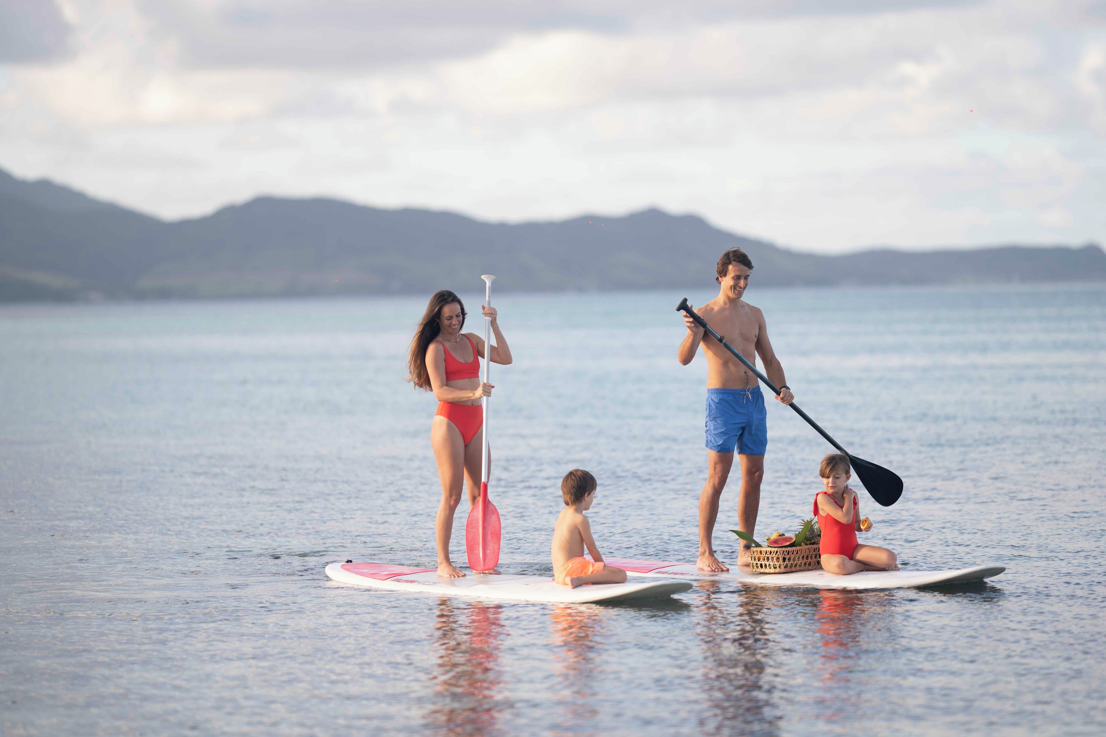 Eine Gruppe von Menschen steht auf Paddleboards auf ruhigem Wasser, im Hintergrund Berge.
