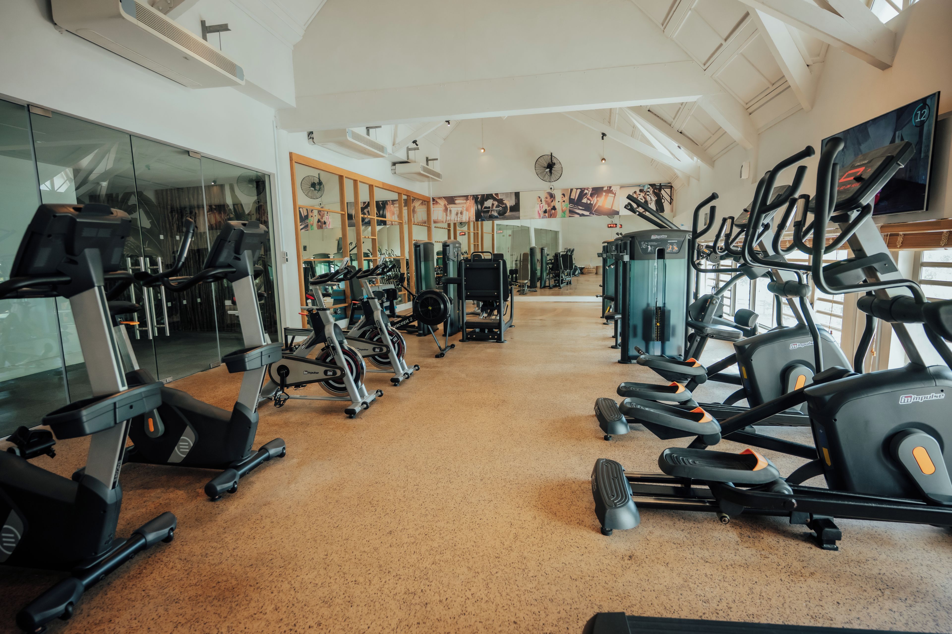 Une salle de sport équipée de plusieurs tapis de course, de vélos d’exercice et d’appareils de musculation.
