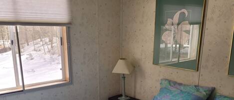 A bedroom with a bed, a nightstand, a lamp, a window, and a framed picture on the wall.