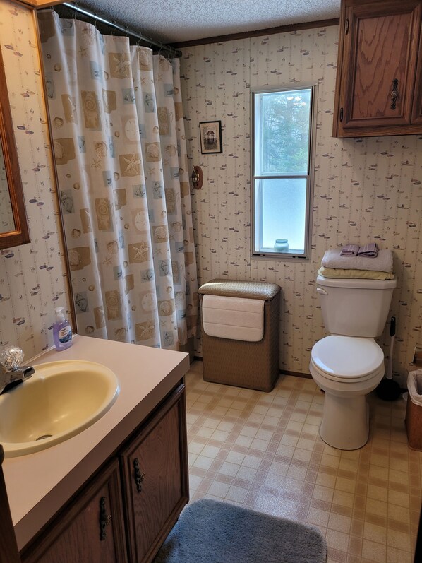 Un baño con inodoro, lavamanos y cortina de ducha.