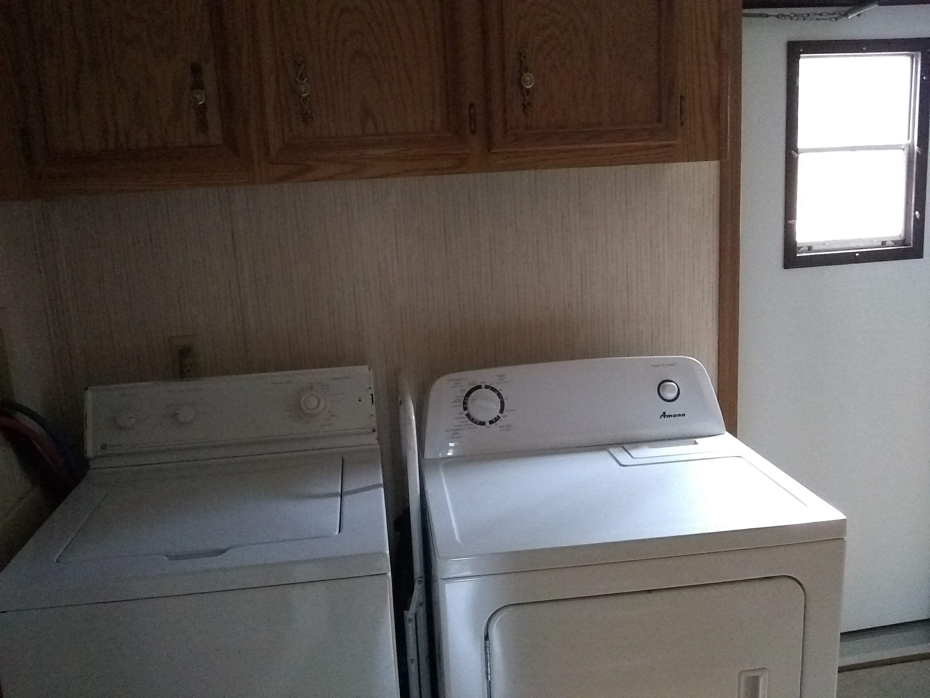 A laundry area with two white washing machines and wooden cabinets above.