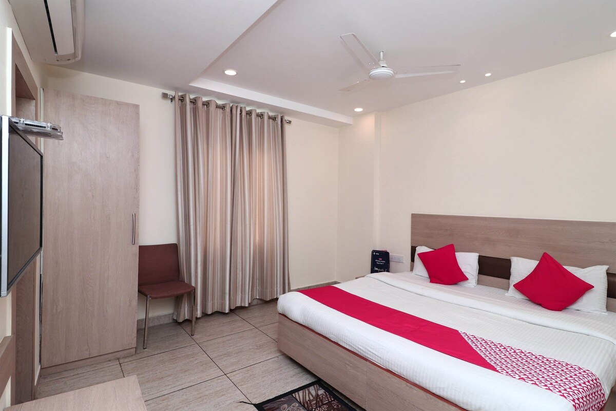 A hotel room with a bed, a wardrobe, a seating area, and a curtain.
