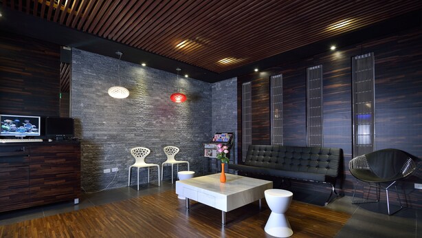 A modern lobby with a wooden ceiling, a stone wall, a sofa, a coffee table, and two chairs. - Hotel Cloud Riverside (New Taipei City)