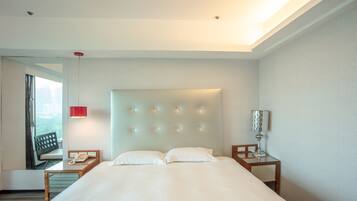 A hotel room with a large bed, a bedside table with a lamp, and a window with curtains.