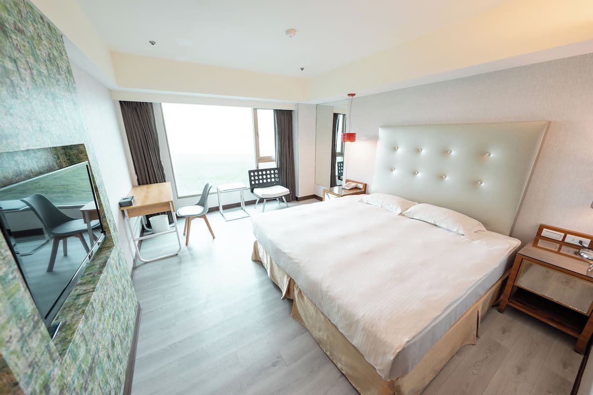 Una habitación de hotel moderna con una cama grande, un escritorio, una silla y un televisor.