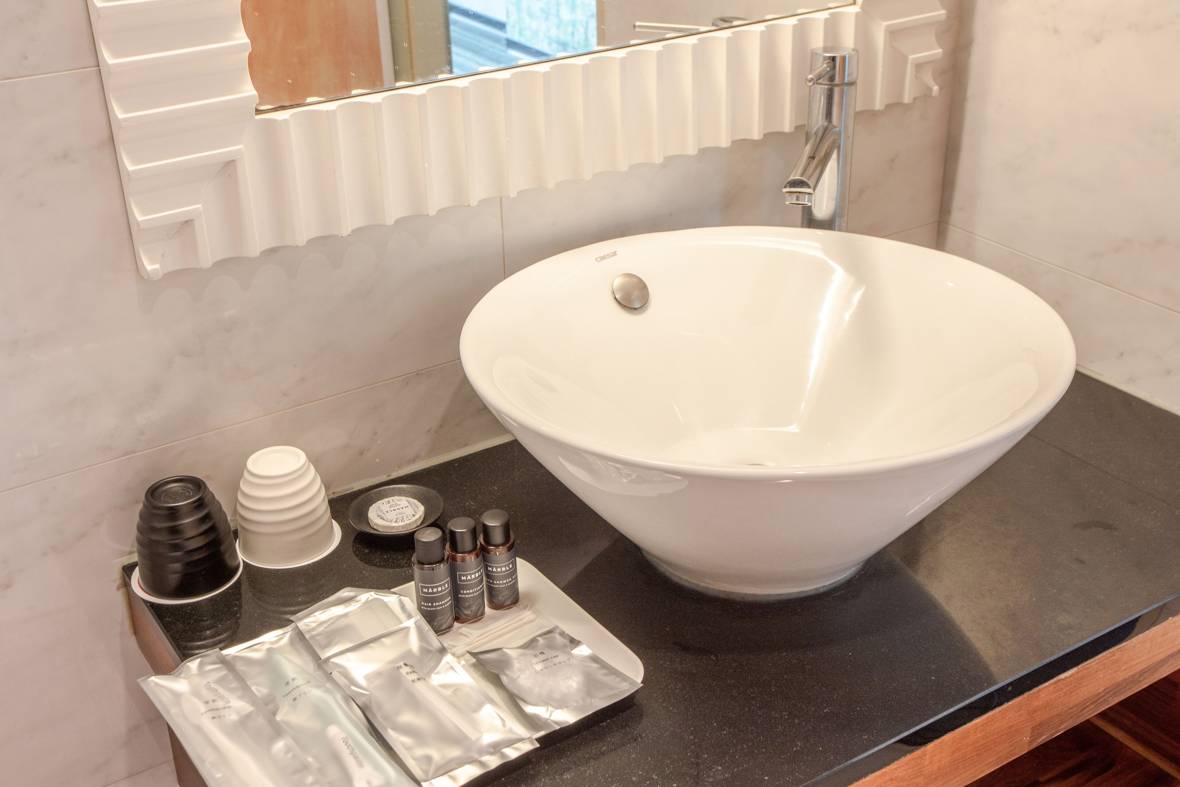 A bathroom with a white sink, a mirror, and toiletries on the counter.