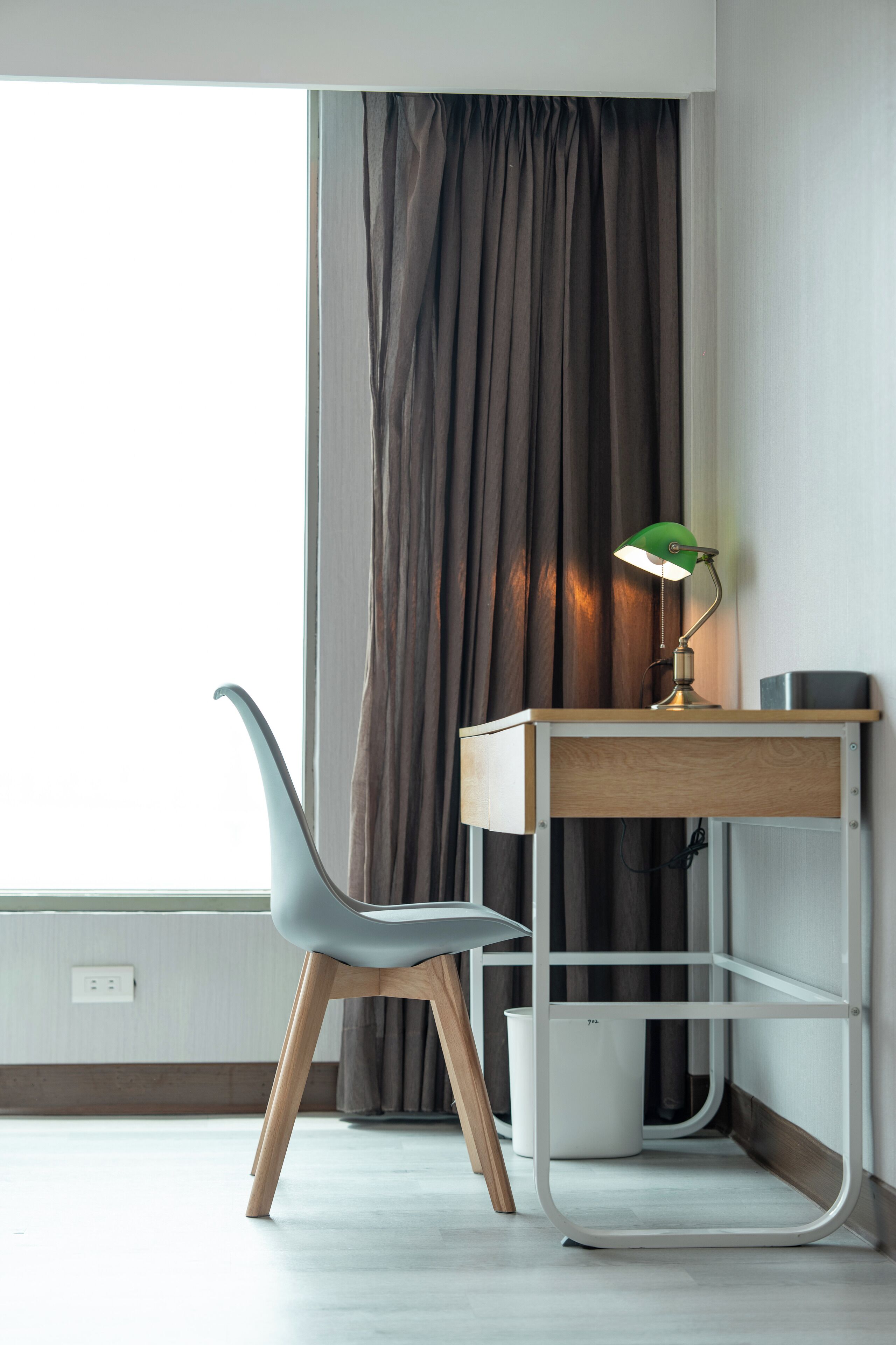 Un'area di lavoro moderna con scrivania, sedia e lampada.