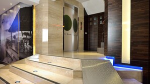 A modern hotel lobby with a marble staircase, wooden paneling, and a reception desk. - Hotel Cloud Riverside (New Taipei City)