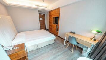 Ein Hotelzimmer mit einem Bett, einem Schreibtisch mit Stuhl, einem Telefon und einem Fernseher.