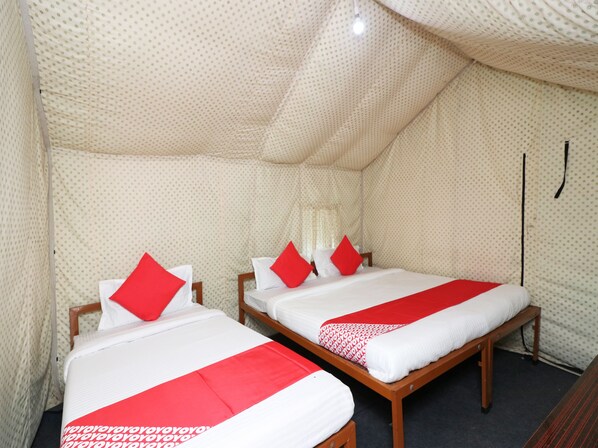 A tent-style room with two beds, each with red and white bedding, and a patterned tent wall.