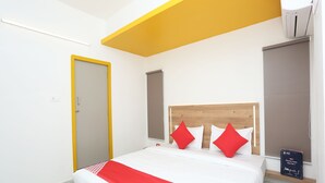 Une chambre d’hôtel moderne avec un grand lit, une tête de lit en bois et un mur d’accent rouge.