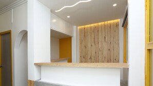 Un espace d’accueil avec un mur recouvert de panneaux de bois, un comptoir d’accueil blanc et un sol en béton.