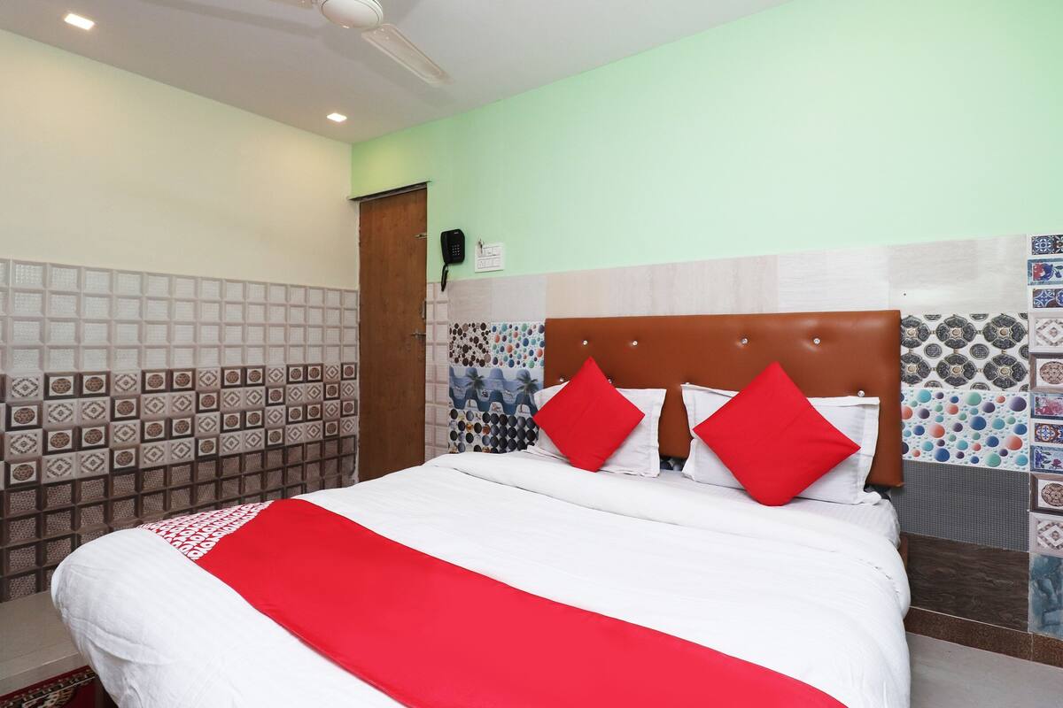 A hotel room with a bed, a wooden headboard, and patterned tiles on the walls.