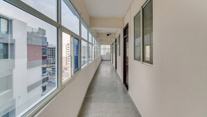 A long, narrow corridor with large windows on one side and a door on the other. - OYO Flagship 29620 New Champion Residency (Bengaluru)