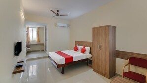 A hotel room with a bed, a wardrobe, a TV, a desk, and a chair. - OYO Flagship 29620 New Champion Residency (Bengaluru)