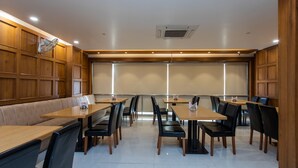 A conference room with wooden paneling, a large table with chairs, and a seating area with a bench. - Capital O 27658 Hotel New Mohit Regency (Bhopal)
