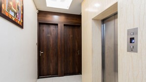 A hallway with a wooden door marked 212, a wooden door marked 214, and an elevator with a digital display showing the number 3. - Capital O 27658 Hotel New Mohit Regency (Bhopal)