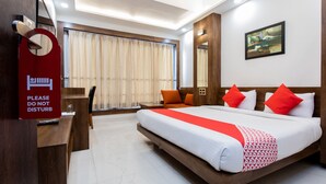 A hotel room with a large bed, a desk, a chair, and a "Please do not disturb" sign. - Capital O 27658 Hotel New Mohit Regency (Bhopal)